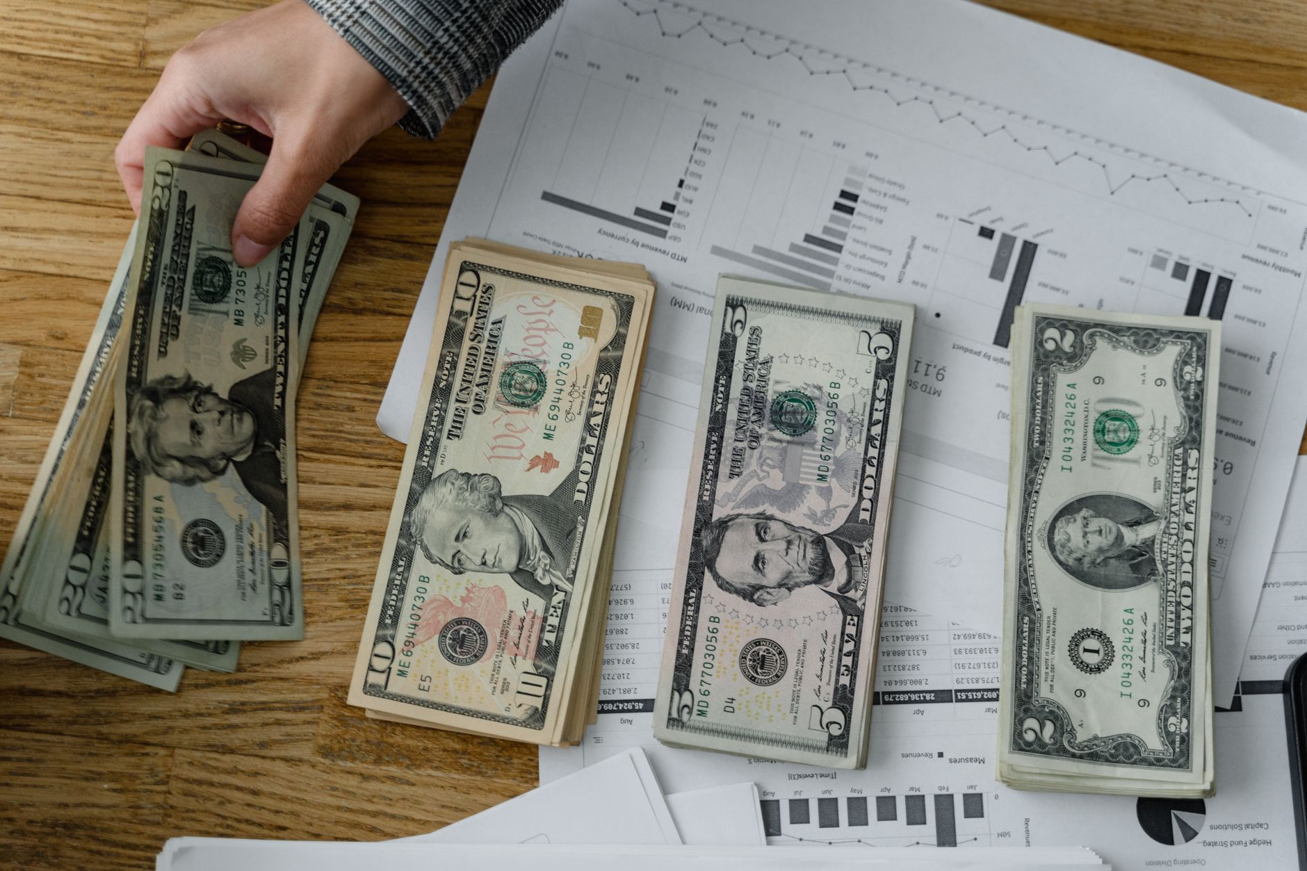 a person holding dollars on the table